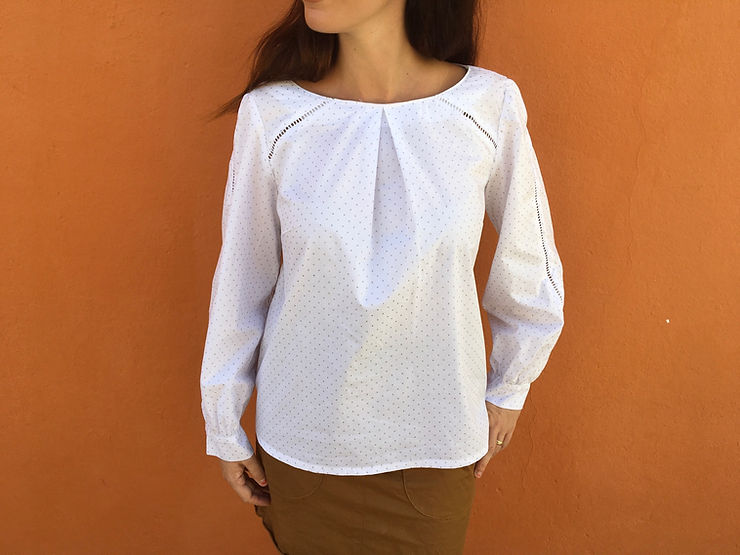 Blouse blanche portée de face, pli creux au milieu devant et jours échelles sur les manches 